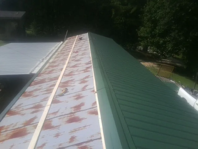 Old rusted panels beside newly installed green metal roofing — Wind Damage Roof Repair by Roofing Brothers in Bloomdale
