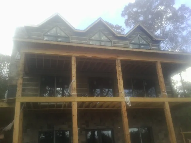 Dormers and porch framing on a large log home under construction — Roof Coating work by our crew in Bloomdale
