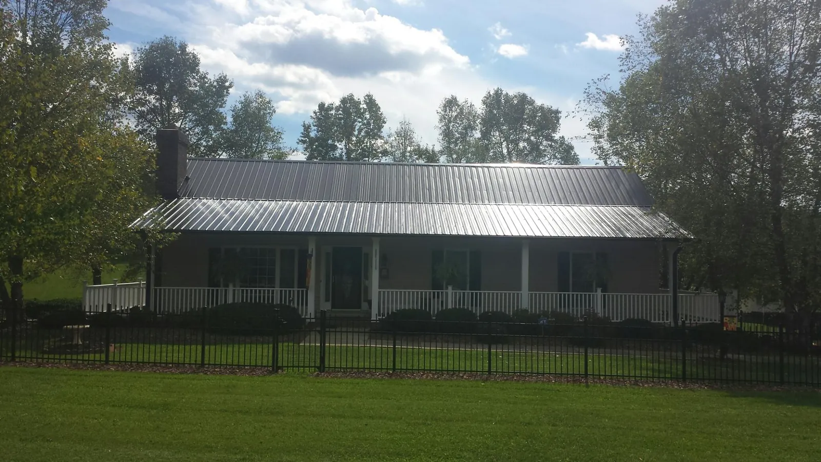 Gray metal roof on a brick ranch with a full width front porch — Gutter Guard Installation work by our crew in Bloomdale