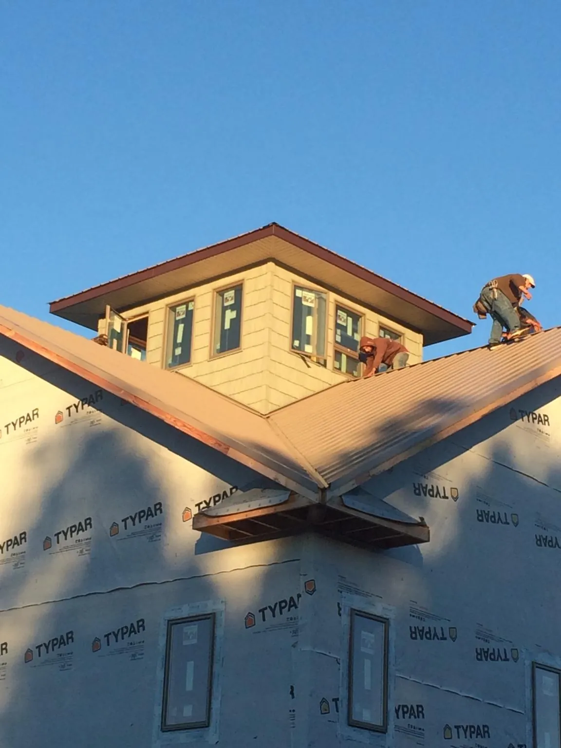 Roofers working around a rooftop cupola on a new metal roof at sunset — Roof Waterproofing in Bloomdale by Roofing Brothers